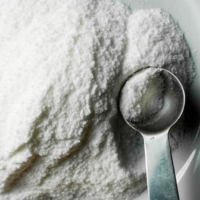 Spoonful of white granules on a pile of white granules
