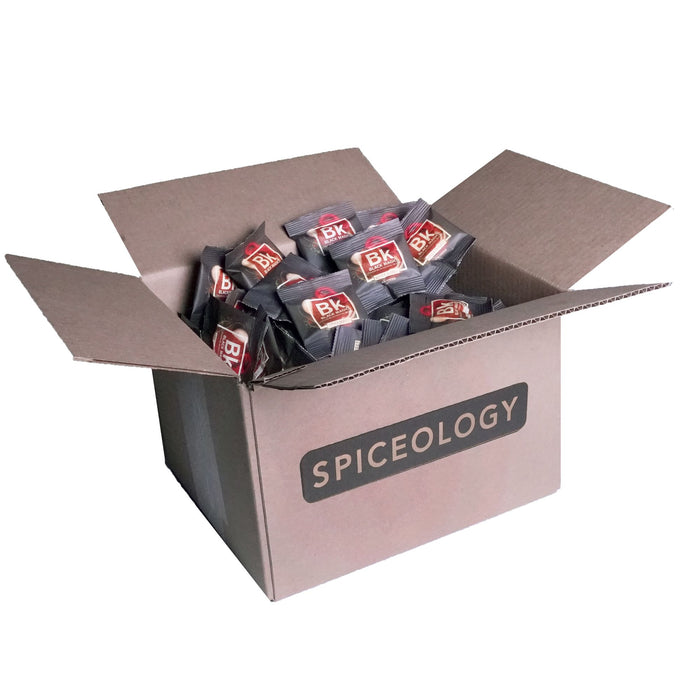 Cardboard box filled with Black Magic packets labeled 'Spiceology' on a white background