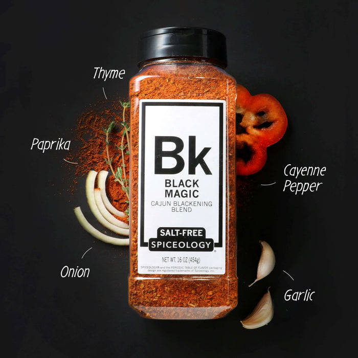 Spiceology Black Magic Salt-Free shaker jar on a dark background with labeled ingredient callouts for Thyme, Paprika, Cayenne Pepper, Onion, and Garlic surrounding the jar