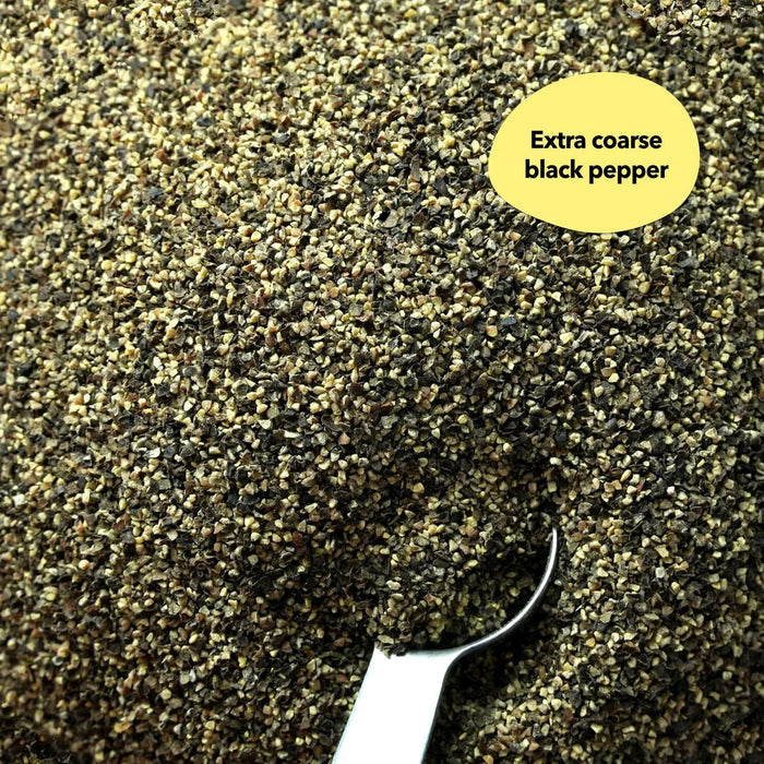 Overhead close-up of coarse black pepper with a silver measuring spoon resting in the blend; a callout reads Extra coarse black pepper