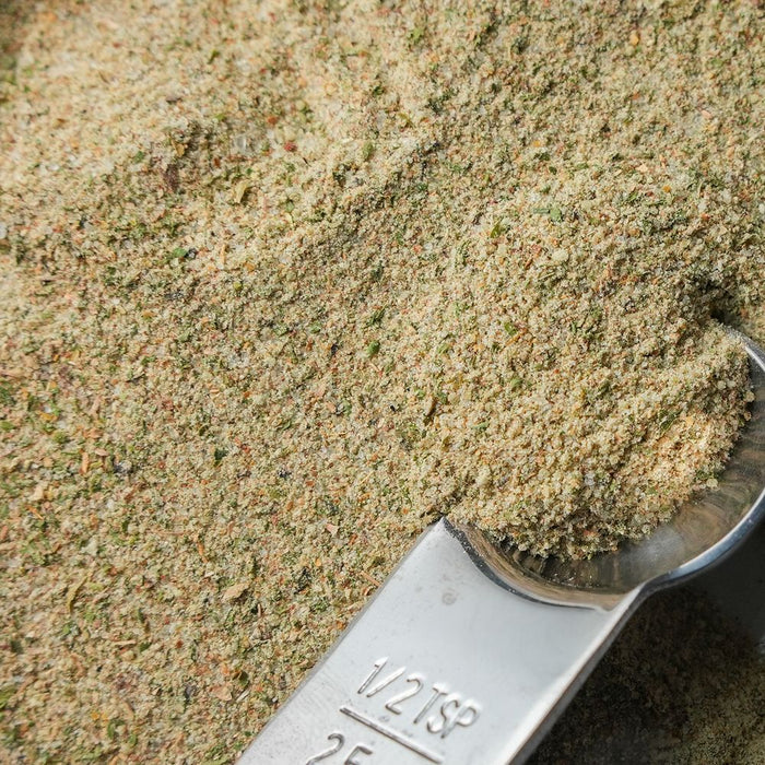 Close-up of a measuring spoon filled with green and yellow ground spice