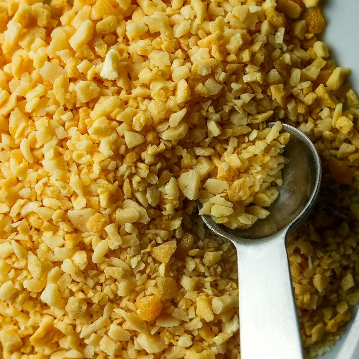 Close-up of a spoonful of yellow crushed carbonated sugar in a pile