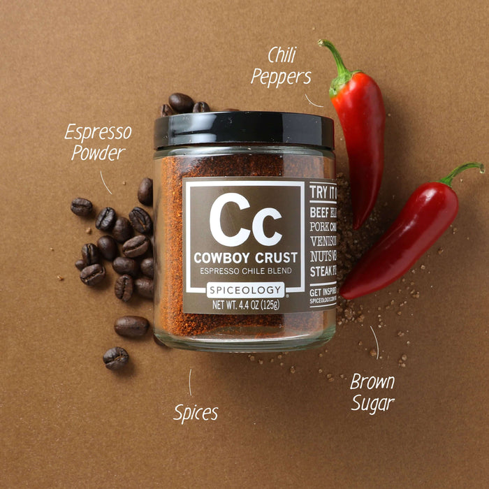 Spiceology Cowboy Crust jar on a dark warm-toned background with labeled ingredient callouts for Espresso Powder, Oil Peppers, Brown Sugar, and Spices; coffee beans and red chilies surrounding the jar
