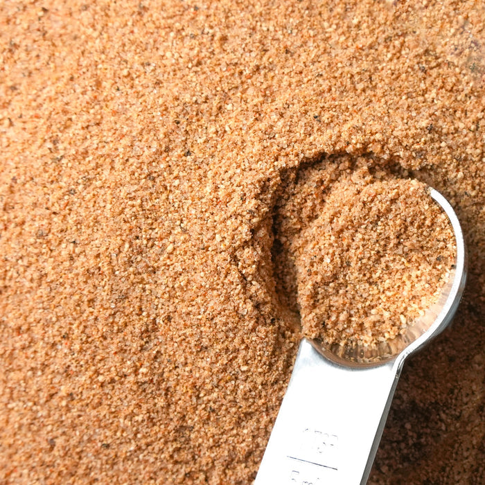 Close-up of a measuring spoon filled with brown spice on a brown spice pile