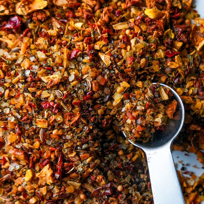 Close-up of a spoonful of mixed spice blend on a pile of spices