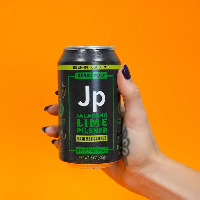 Hand holding a can of Spiceology Derek Wolf Jalapeno Lime Pilsner beer-infused rub against an orange background