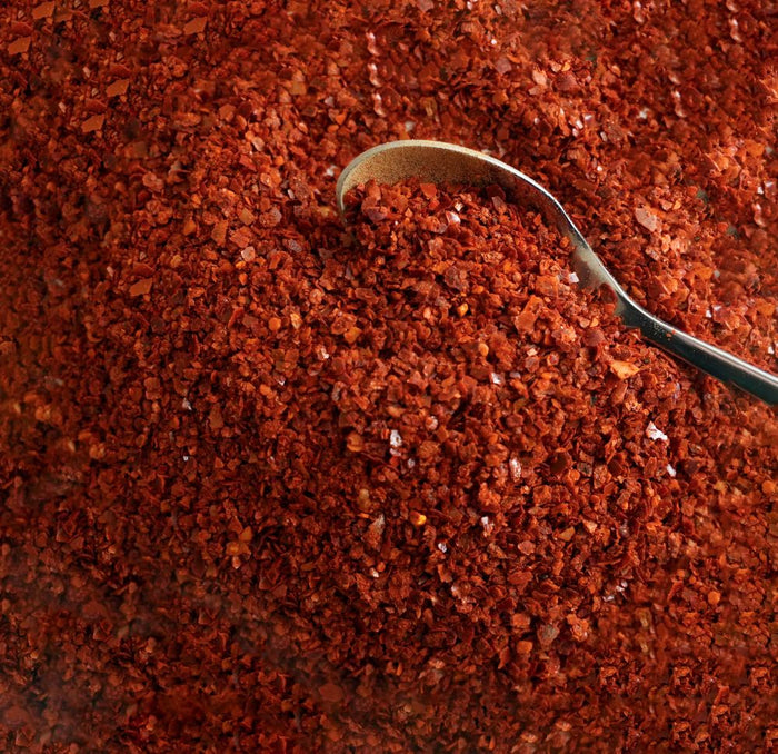 Close-up of ground red spice flakes with a spoon