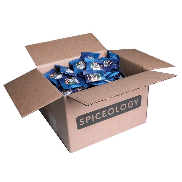 Cardboard box labeled 'Spiceology' filled with Greek Freak Mediterranean packets on a white background