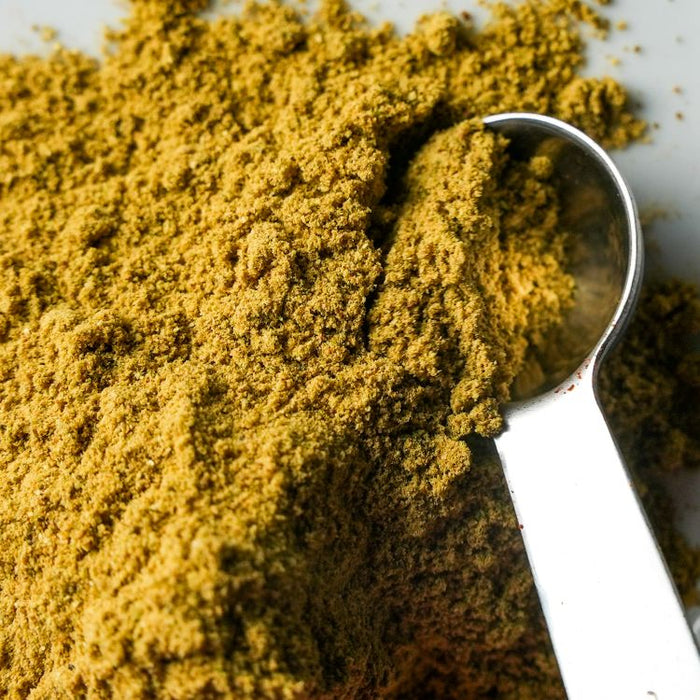 Close-up of a spoonful of yellow powder on a white background