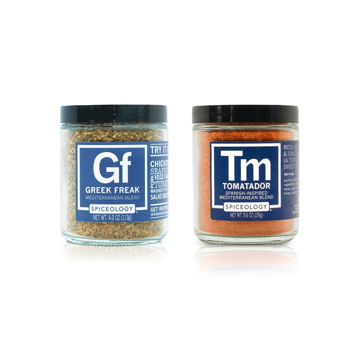 Two jars of spice mix, one labeled Greek Freak' and the other 'Tomatador', on a white background.