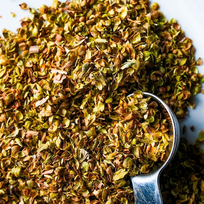 Dry green herbs in a spoon on a white background
