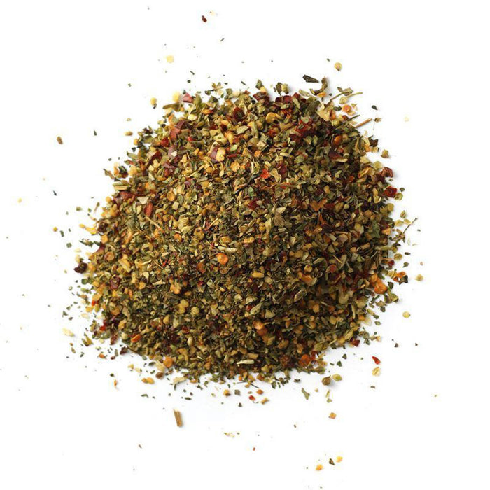 Closeup of green leafy spice with red, orange and yellow flakes mixed in