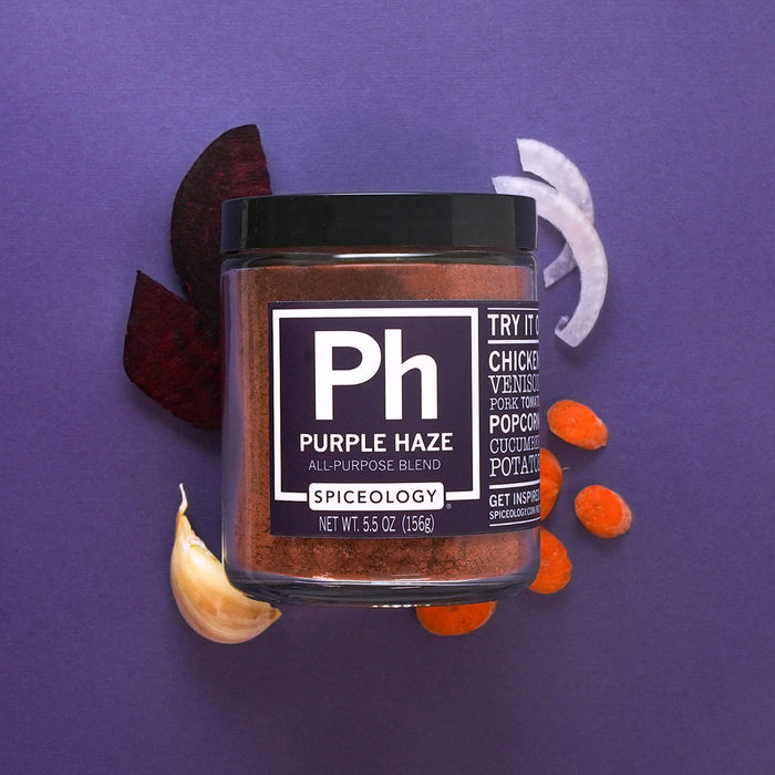 Jar of Spiceology purple haze on a purple background with slices of beets, carrots, onion and a garlic clove