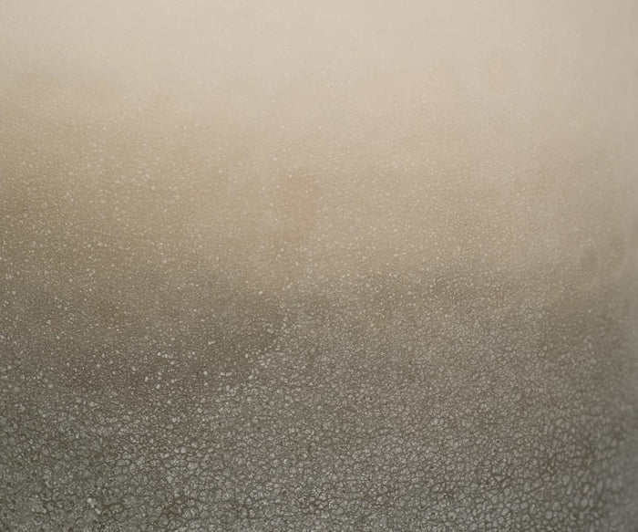 A close-up of a hand-finished glass surface, with condensation droplets forming a textured pattern. The colors transition from light beige at the top to deeper gray at the base, mirroring the delicate tonal shifts characteristic of the Soft Gradient Vase.
