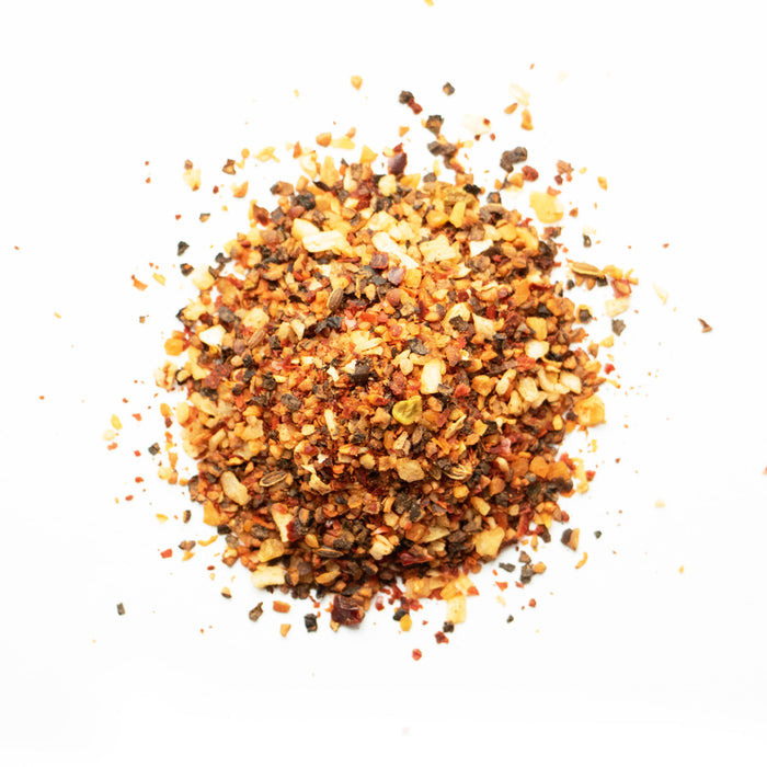 A pile of reddish-orange ground spice powder is spread in a small mound on a white background.
